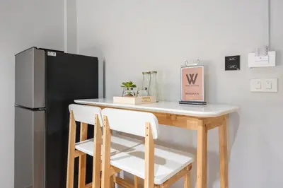 a small kitchen with a table and a refrigerator at Hotel Wizpark Ratchada in Bangkok