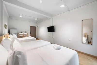 a white room with two beds and a mirror at Hotel Wizpark Ratchada in Bangkok