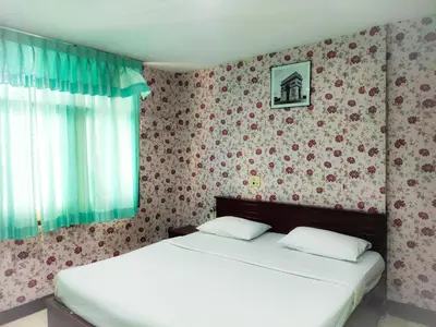 a bedroom with two beds and a wall with flowers at Woodlands Inn in Bangkok