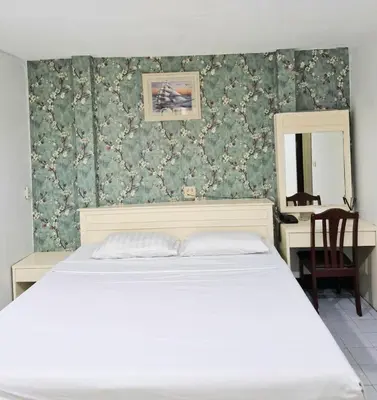 a bedroom with a bed and a desk with a mirror at Woodlands Inn in Bangkok