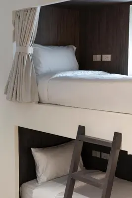 a bedroom with two bunk beds and a chair at Lilit Bang Lumphu Hotel in Bangkok