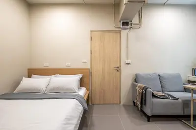a bedroom with a bed and a chair and a door at C2 stay Phayathai in Pom Prap