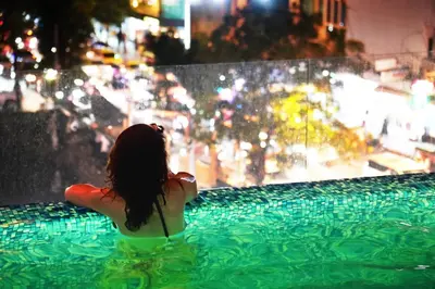 a woman in a swimming pool looking at a city at The Rich Residence Sukhumvit Nana in Bangkok