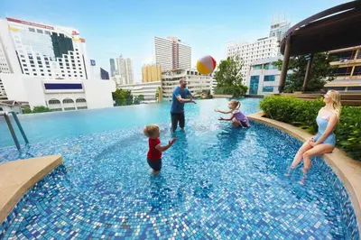 a family playing with a ball in a swimming pool at The Rich Residence Sukhumvit Nana in Bangkok