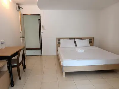 a bedroom with a bed and a table and a desk at Grandview Condominia in Bangkok