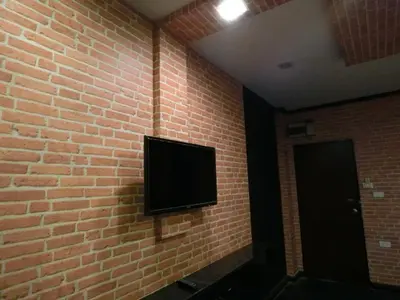 a flat screen tv on a brick wall at NewYork Suite Hotel in Ban Ko
