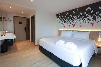 a bedroom with a large white bed and a bathroom at KOO HOTEL in Ban Bang Talat