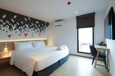 a bedroom with a bed and a desk and a window at KOO HOTEL in Ban Bang Talat