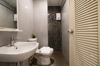 a bathroom with a sink and a toilet and a shower at Amber Inn in Bangkok