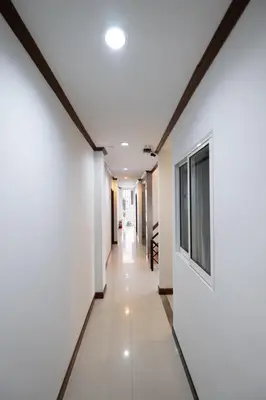 a hallway in a building with white walls and a television at Amber Inn in Bangkok