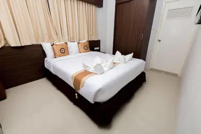 a bedroom with a large white bed with brown pillows at Royal Asia Hotel Pratunam in Bangkok