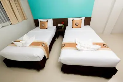 two beds in a hotel room with white and brown pillows at Royal Asia Hotel Pratunam in Bangkok