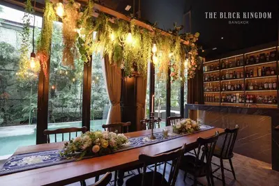 a long table in a bar with chairs and lights at The Black Kingdom - เดอะ แบล็ค คิงดอม in Bangkok