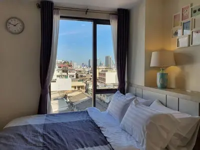a bedroom with a bed and a window with a clock at I'M Chinatown Residence Yaowaraj Bangkok Watmungkorn MRT Station in Bangkok