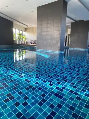 a swimming pool with blue tiles on the floor at 29th floor Studio, Cozy Workplace, Long stay, wide space in Amphoe Phra Khanong