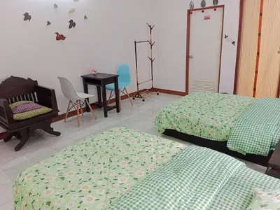 a bedroom with two beds and a table and a chair at Worakarn Apartment 2 in Bangkok