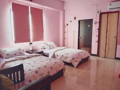two beds in a room with pink walls at Worakarn Apartment 2 in Bangkok