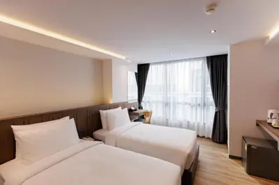 a hotel room with two beds and a window at Pure Eleven Hotel Bangkok in Bangkok