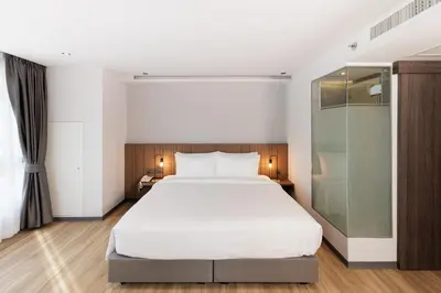 a bedroom with a white bed and a glass shower at Pure Eleven Hotel Bangkok in Bangkok