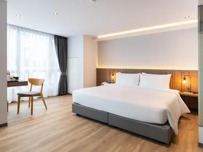 a bedroom with a large white bed and a desk at Pure Eleven Hotel Bangkok in Bangkok