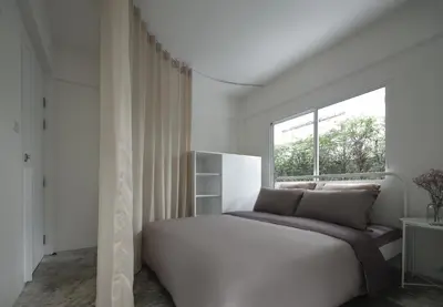 a white bedroom with a large bed and a window at InJoy Snow Hotel in Ban Chuat Plai Mai
