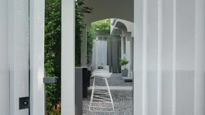a white stool sitting in a courtyard through a door at InJoy Snow Hotel in Ban Chuat Plai Mai