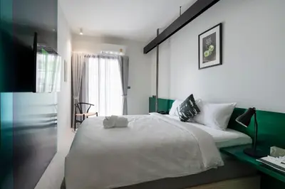 a bedroom with a large white bed and a window at Hotel Sapin in Pom Prap