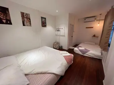 a bedroom with two beds with white sheets and wood floors at 77 Old Town in Bangkok