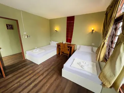 a small room with two beds and a table at DonMueang Boutique House DonMueang Airport in Bangkok