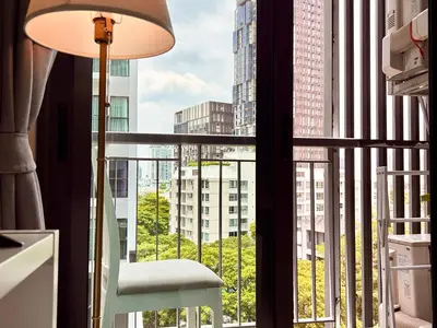 a room with a window with a chair and a view of a city at Rhythm sukhumvit 36 two bedrooms in Bangkok