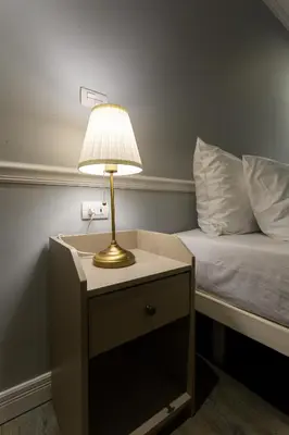a lamp on a night stand next to a bed at Baansuansao in Bang Rak