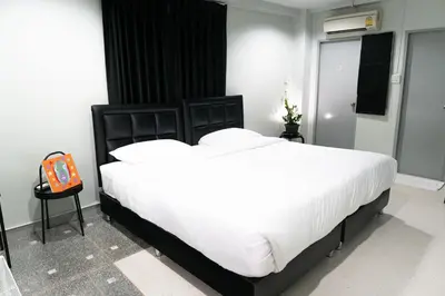 a bedroom with a large bed with white sheets at Suksomboon Residence in Bangkok