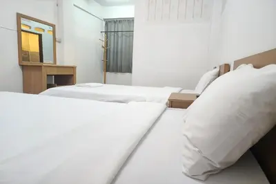 two white beds in a room with a mirror at Green Apartment Kaset in Bangkok