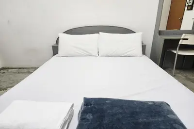 a bed with white sheets and pillows in a room at Green Apartment Kaset in Bangkok