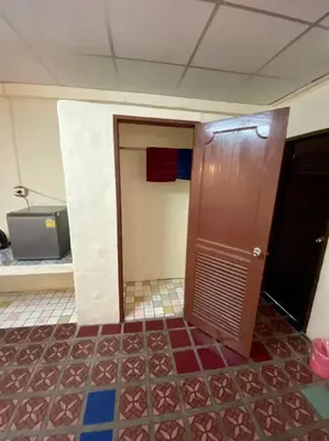 a bathroom with a wooden door and a tiled floor at Ratanawong Place 407 in Bangkok