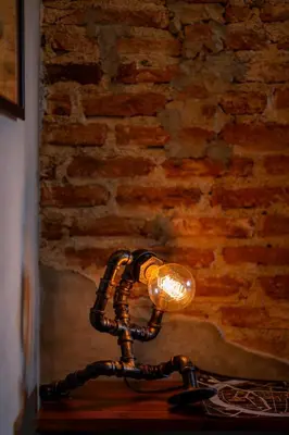 a lamp sitting on a table in front of a brick wall at House of Machine Boutique Hotel in Bangkok