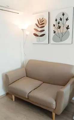 a couch in a living room with two pictures on the wall at Elio Del Ray in Bangkok