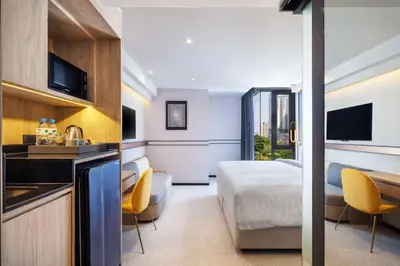 a hotel room with a bedroom and a bed and a kitchen at Best Western Ratchada Hotel in Bangkok