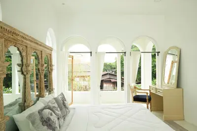 a bedroom with a bed and large windows at Arpo Pool Villa Riverside Bangkok in Bangkok