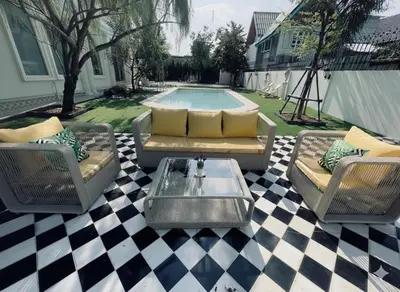 a patio with couches and a table and a pool at Arpo Pool Villa Riverside Bangkok in Bangkok