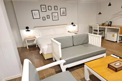 a bedroom with a bed and a couch and a table at J PLACE HOTEL in Bangkok