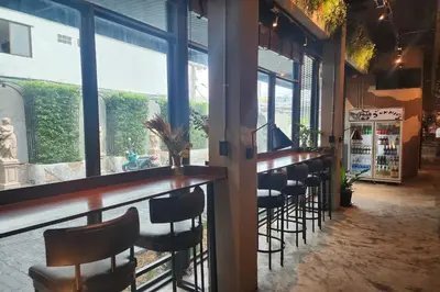 a bar with a row of bar stools in a restaurant at J PLACE HOTEL in Bangkok