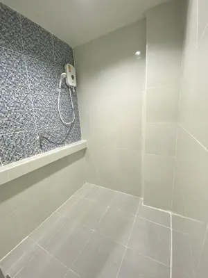 a white bathroom with a shower and a phone at บ้านสายสิริ in Ban Bang Talat