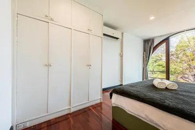 a bedroom with white cabinets and a large window at Bangkok Cozy Garden Pool Villa Sukhumvit in Amphoe Phra Khanong