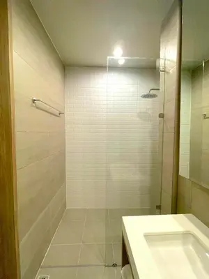 a bathroom with a glass shower and a sink at Silom Nara in Bangkok