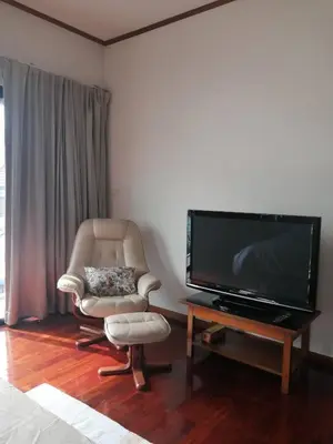 a living room with a chair and a flat screen tv at AP HOUSE in Bangkok