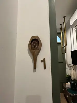 a wooden door knocker on a white wall at Ci home in Pom Prap