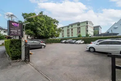 a parking lot with cars parked in front of a building at Synsiri Lat Phrao 83 in Ban Zong Katiam