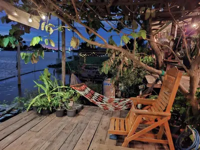 a hammock and a chair sitting on a deck at Baan GoLite Ko Kret - บ้านโกไล้เกาะเกร็ด in Nonthaburi