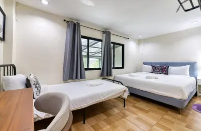 two beds in a room with a table and chairs at Bangkok Watergate Townhouse \u66fc\u8c37\u4e2d\u5fc3\u6c34\u9580\u5bb6 in Bangkok